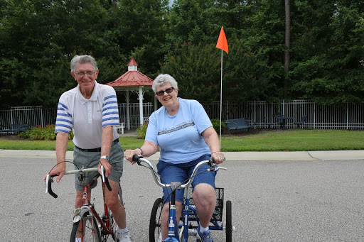 An elderly couple enjoying a sunny day cycling together.