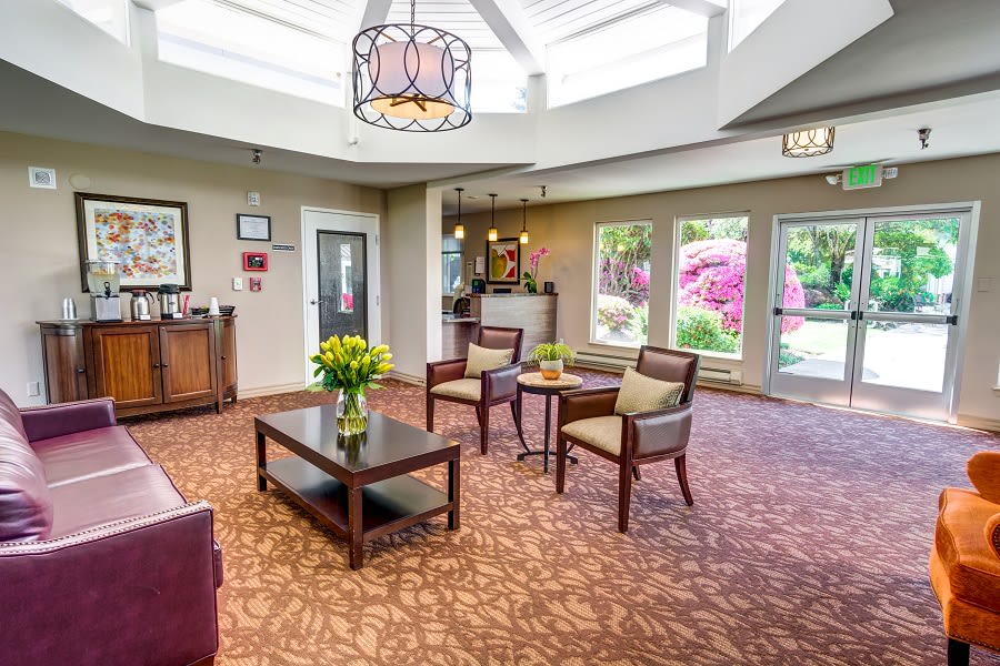 A well-lit lobby featuring comfortable seating and a coffee table with flowers.