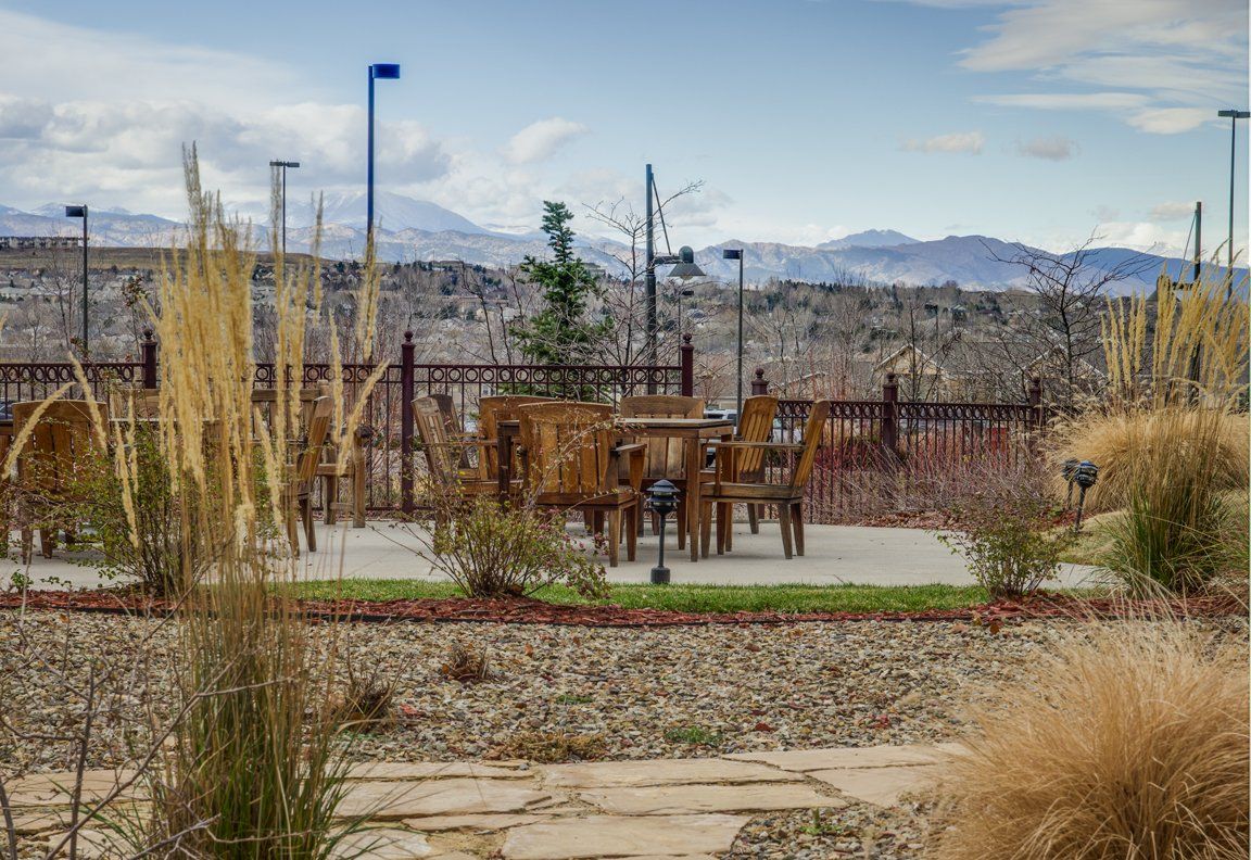 An outdoor seating area with wooden furniture, surrounded by nature and overlooking distant mountains.