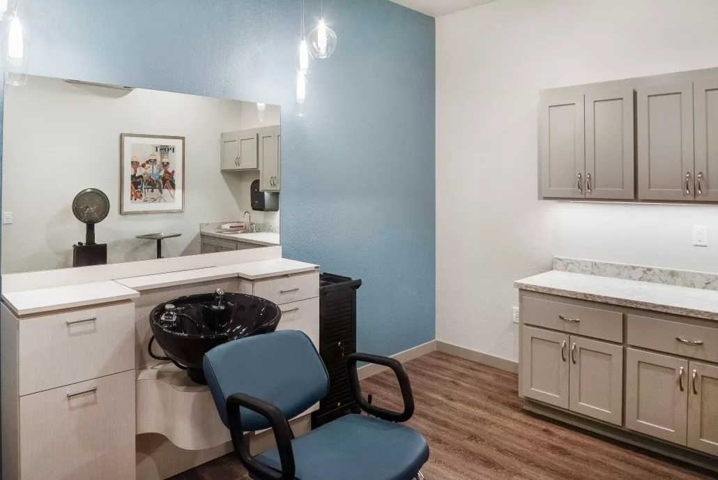 A modern hair salon interior with a styling chair, mirror, and sink.