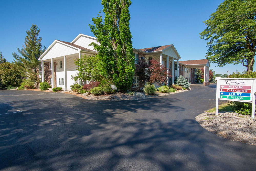 A residential building with well-maintained landscaping and a spacious driveway on a sunny day.