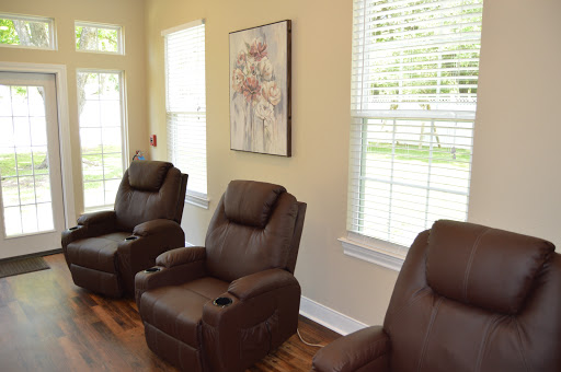 A cozy living area featuring comfortable brown recliners and a serene piece of artwork, illuminated by natural light from the large windows.