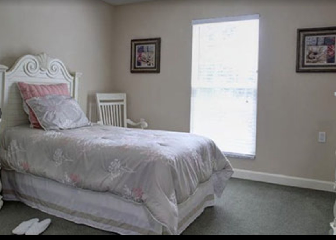 A minimalist bedroom with a single bed and a window letting in natural light.