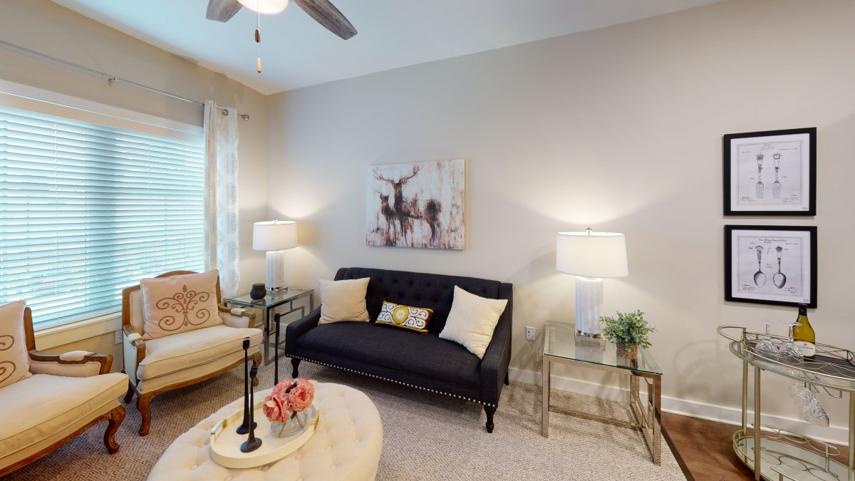 A cozy living room with modern decor, featuring a black sofa, stylish coffee table, and elegant lighting.