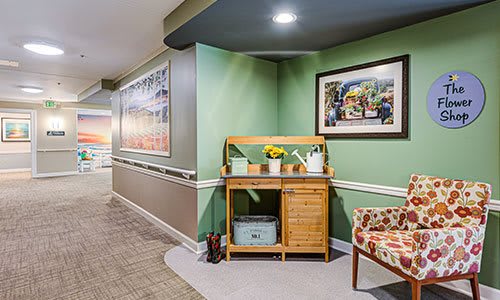 A cozy interior hallway featuring green walls, decorated with framed artwork and wooden furniture.