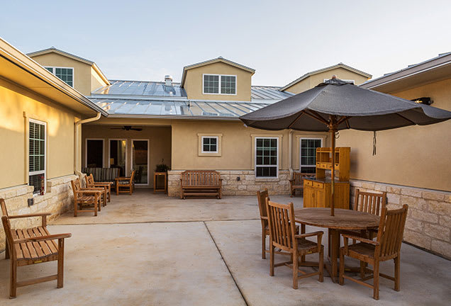 A spacious patio with outdoor furniture and an umbrella in front of a modern house.