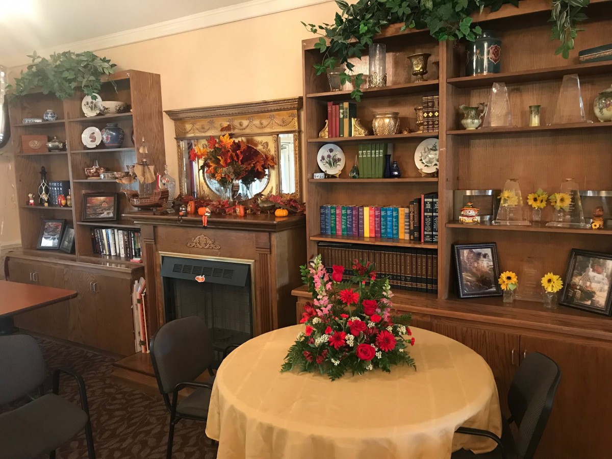 A cozy room with a decorated bookshelf and table featuring a floral centerpiece.