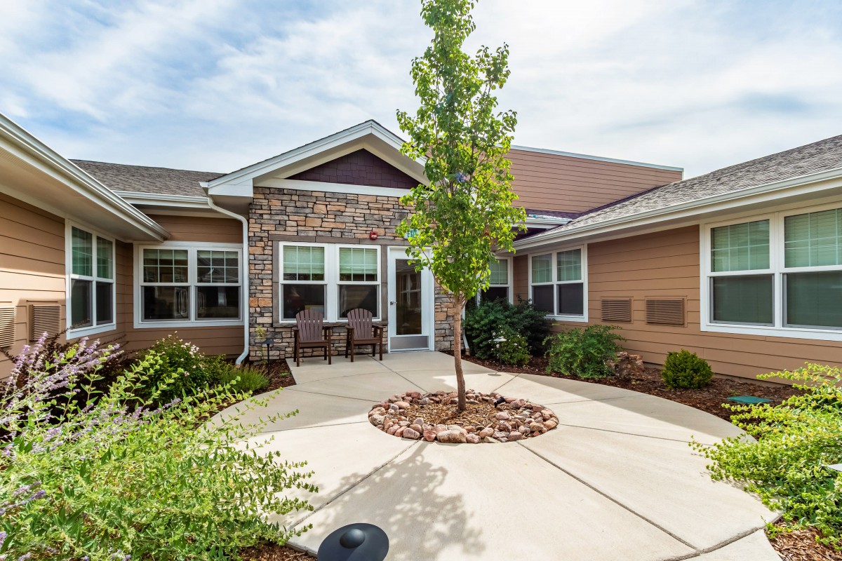 A welcoming house entrance with a central tree and brick facade.