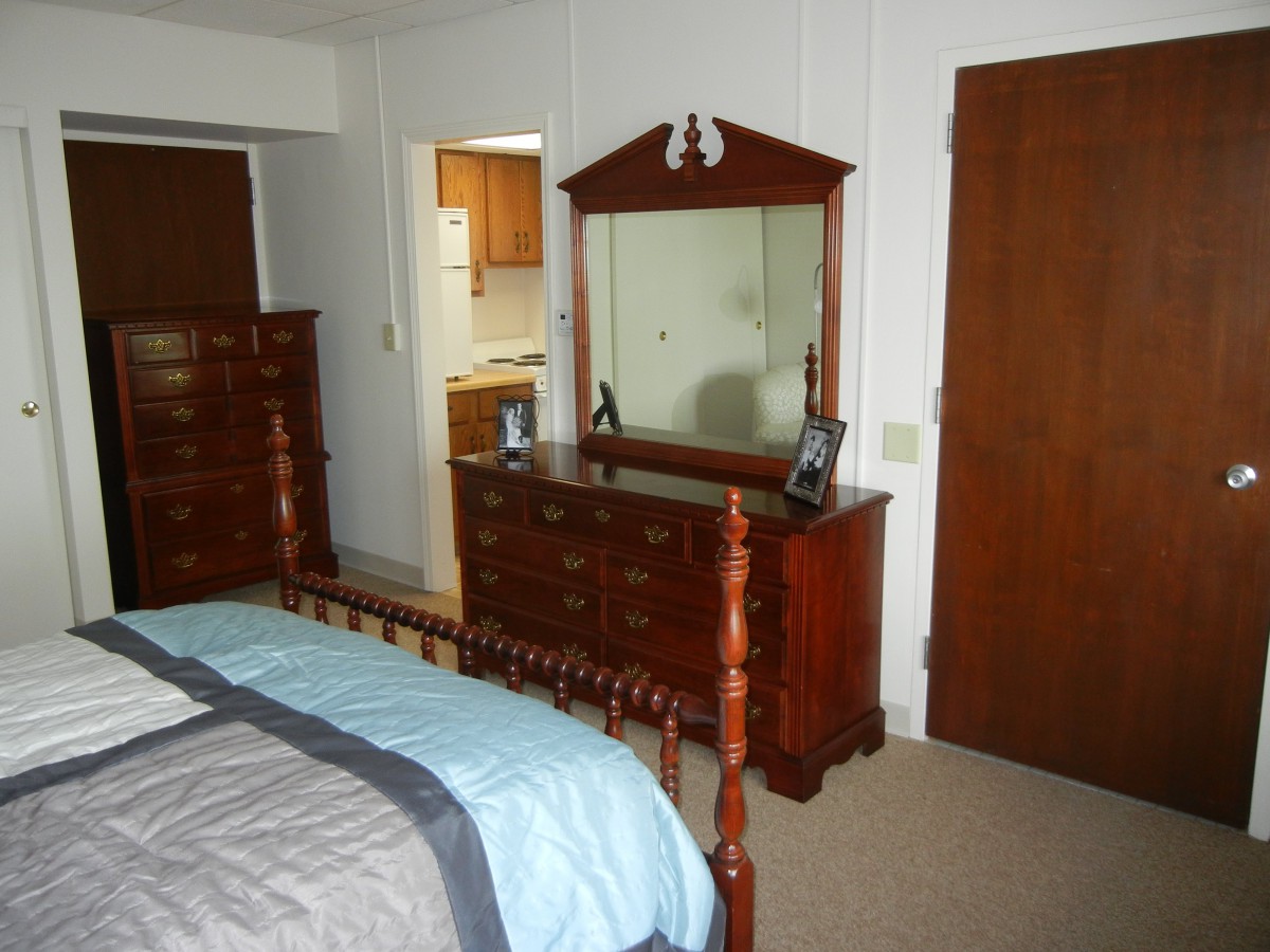 A bedroom featuring a wooden bed and dresser with a mirror.