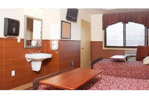 A small hotel room with a bed, sink, and television.