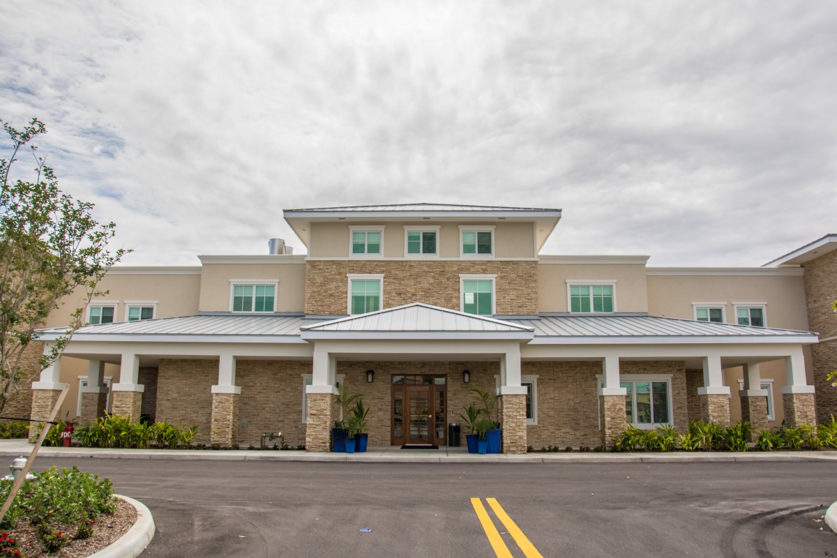 Front view of a modern building with a covered entrance and a cloudy sky overhead.