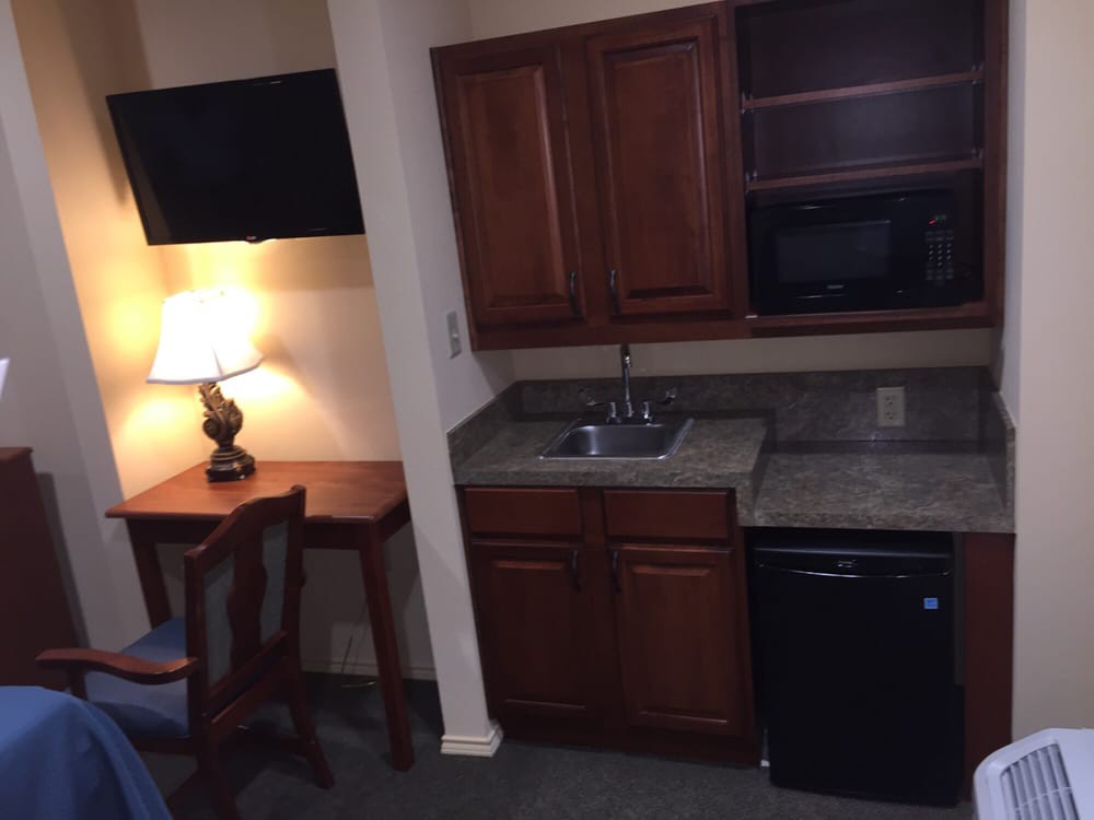 A small hotel room kitchenette with a desk, television, and basic amenities.