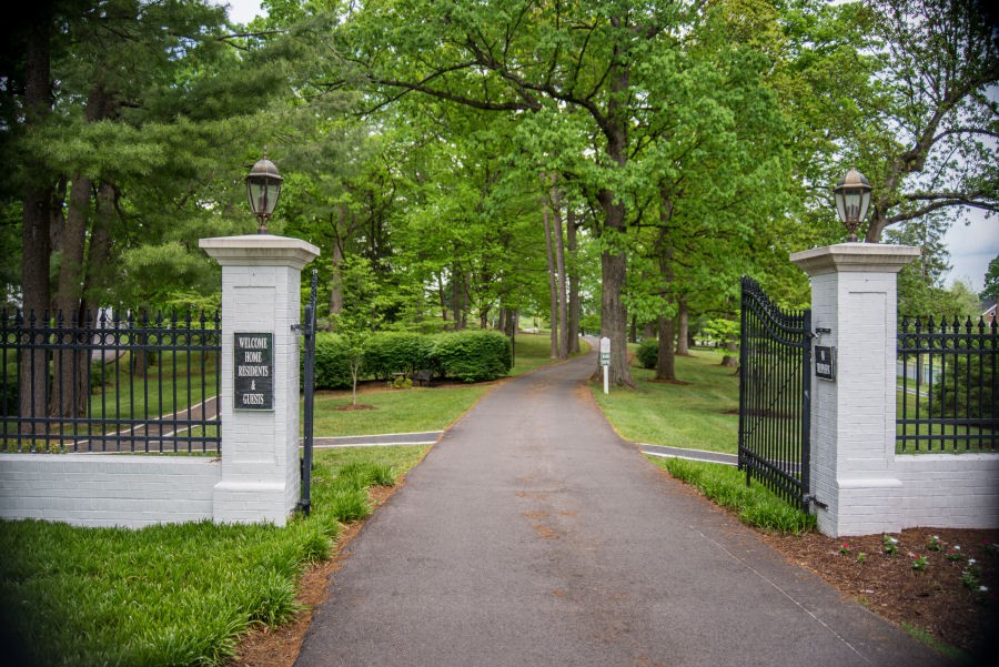 A serene entrance with open gates leading to a tree-lined pathway.