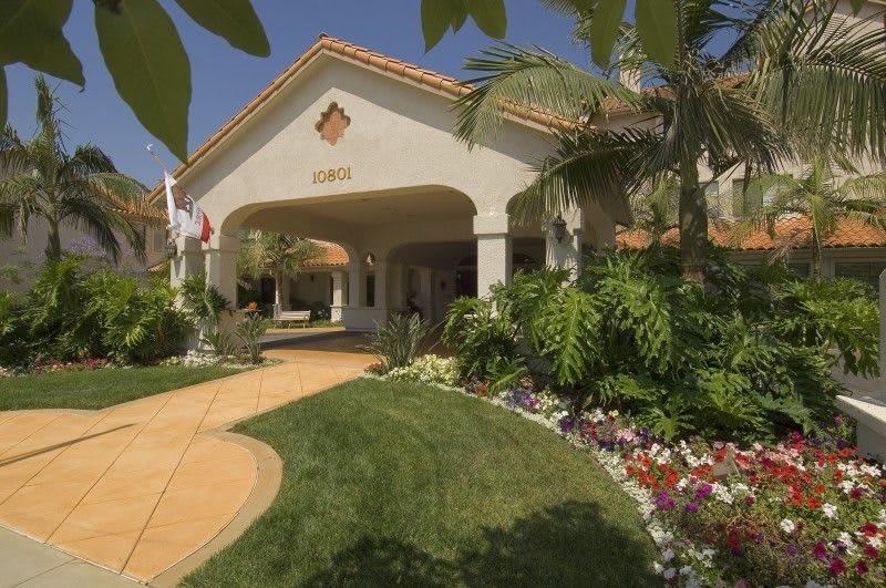 A well-landscaped building entrance with greenery and flowers.