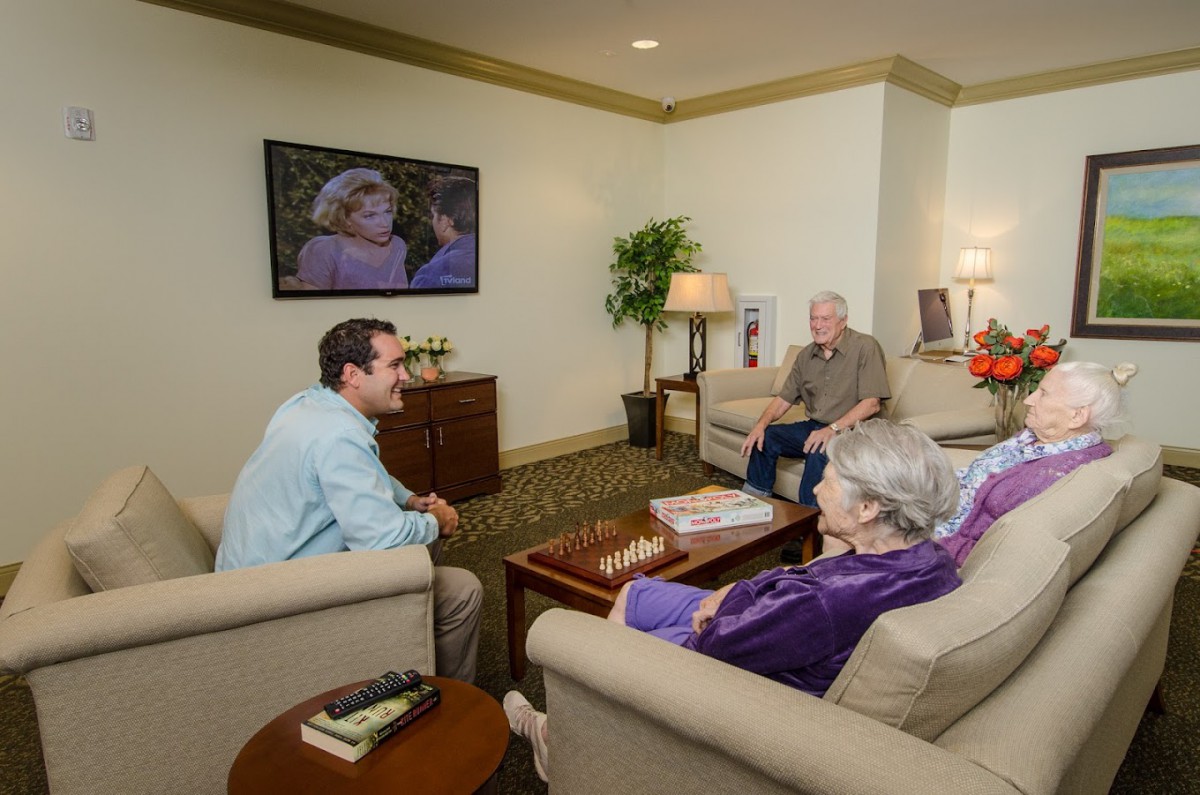 A group of people enjoying a conversation in a cozy living room while watching TV.