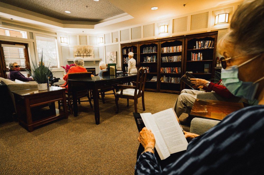 A cozy library setting with seniors reading and relaxing among shelves of books.