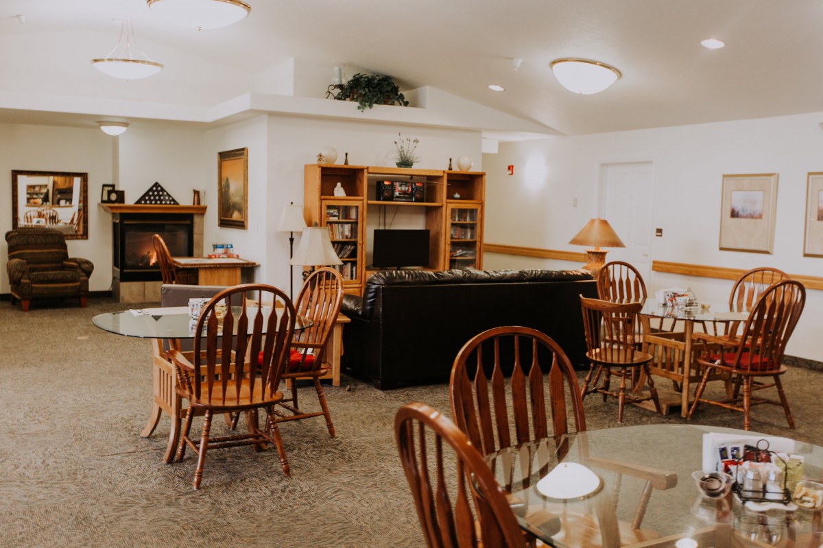 A cozy living area featuring wooden chairs, a dining table, bookshelves, and a fireplace.