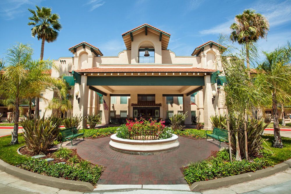 A grand hotel entrance surrounded by lush landscaping and palm trees.