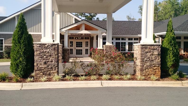 A well-designed building entrance with stone columns and landscaped surroundings.