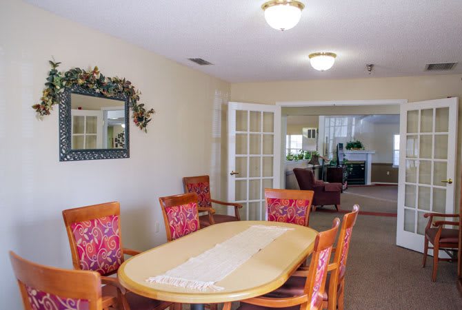 A cozy dining room with wooden table and red upholstered chairs.
