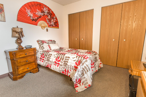 A cozy bedroom featuring a patterned bedding set, wooden furniture, and decorative wall art.