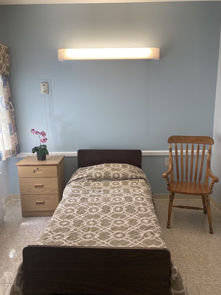 A minimalist bedroom with a single bed, nightstand, and a wooden chair.