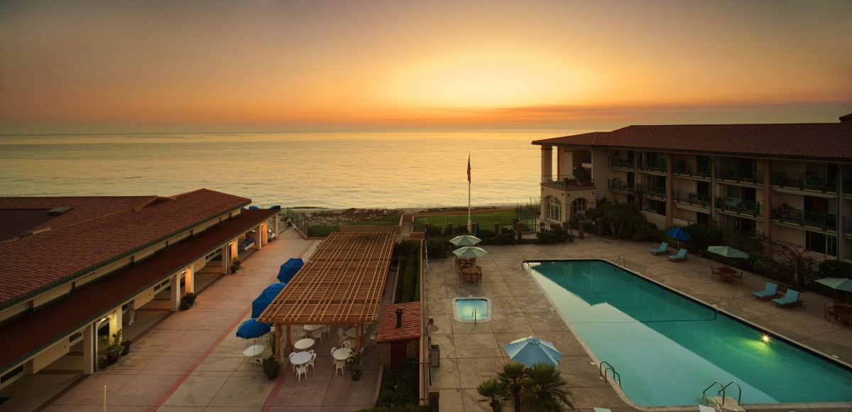 A serene beachfront resort with a pool overlooking a beautiful sunset.