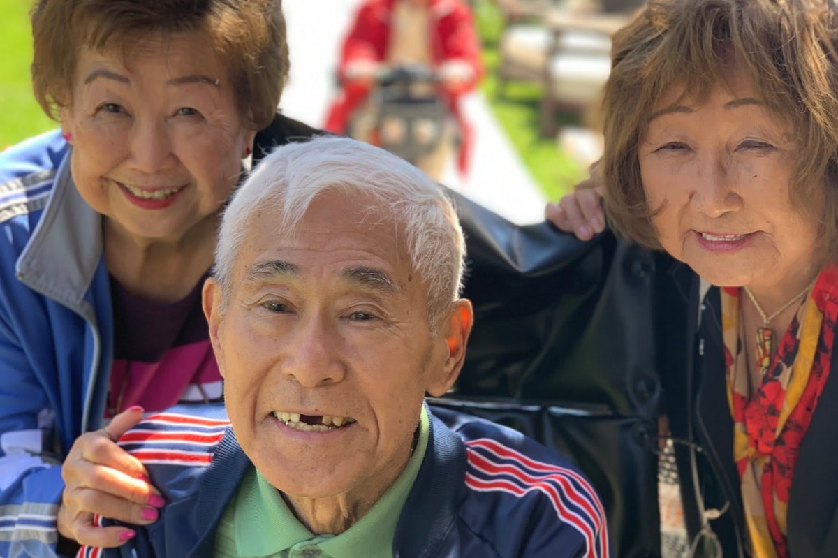 A group of elderly people smiling and enjoying time outdoors.