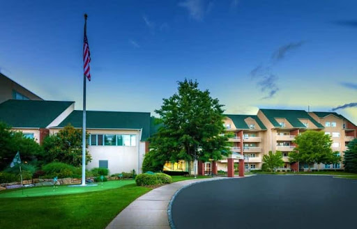 A serene view of a hotel with a flag, surrounded by greenery during twilight.
