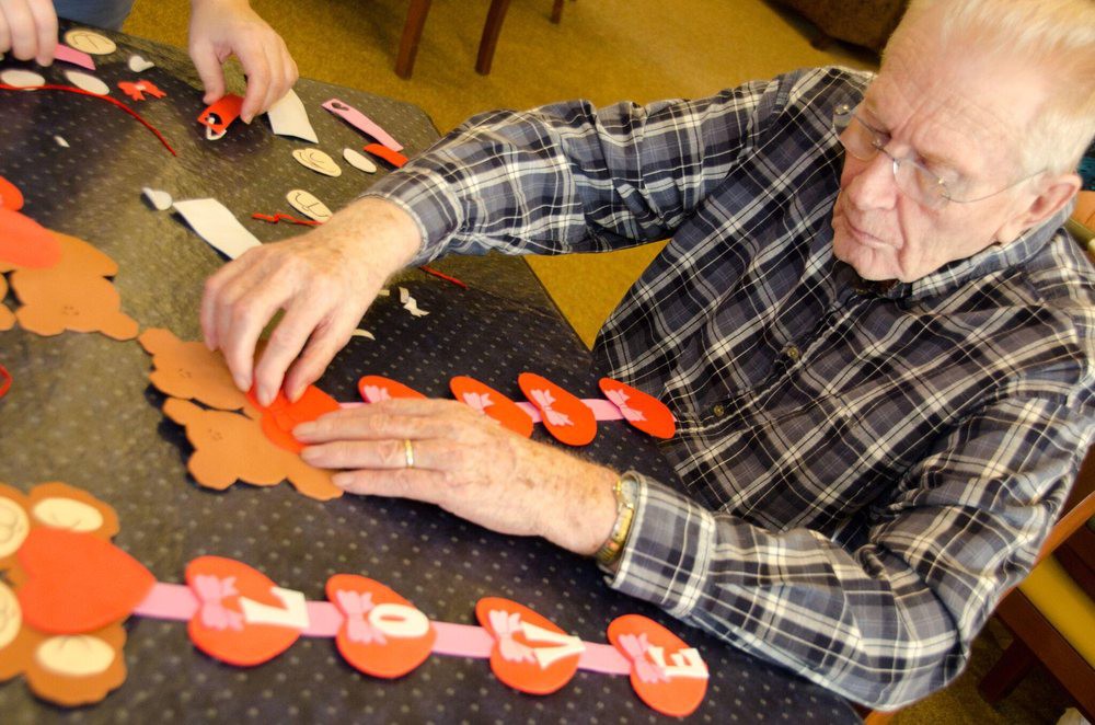 An elderly person engaged in a crafting activity, arranging paper heart decorations.