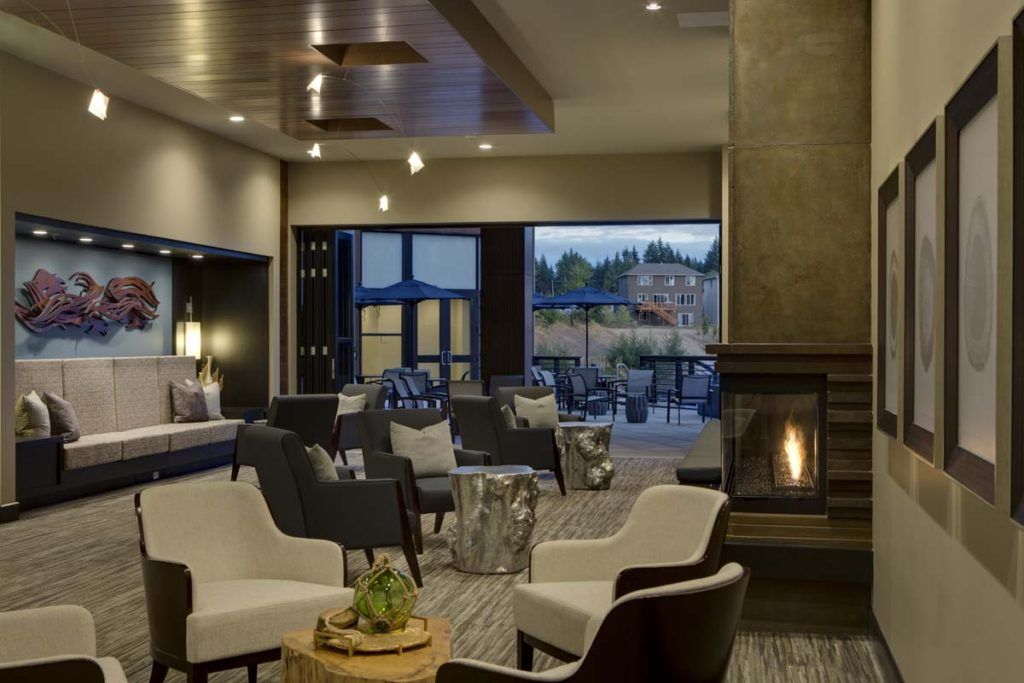 A modern and cozy lounge area featuring comfortable seating and a fireplace, with large windows offering natural light.