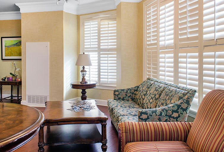 A cozy living room with patterned furniture and elegant window shutters.
