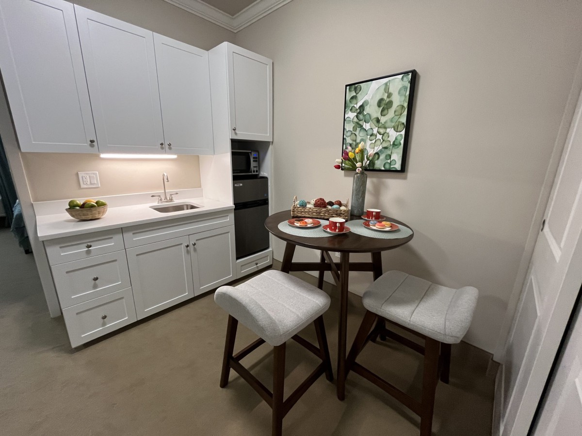 A cozy kitchen with a modern dining area featuring a round table and cushioned stools.