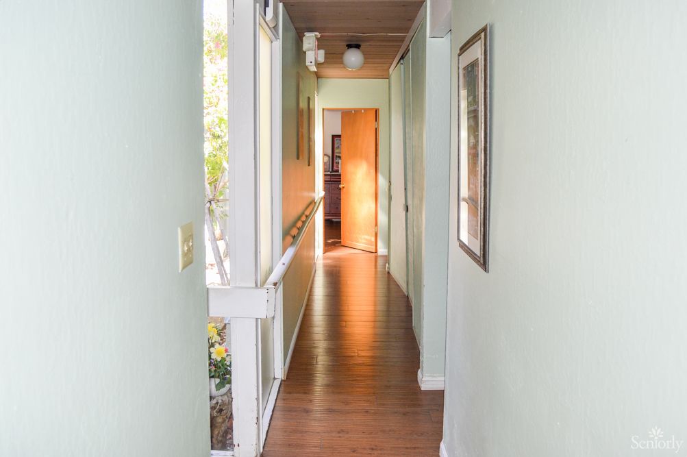 A bright hallway with wooden flooring and a door at the end.