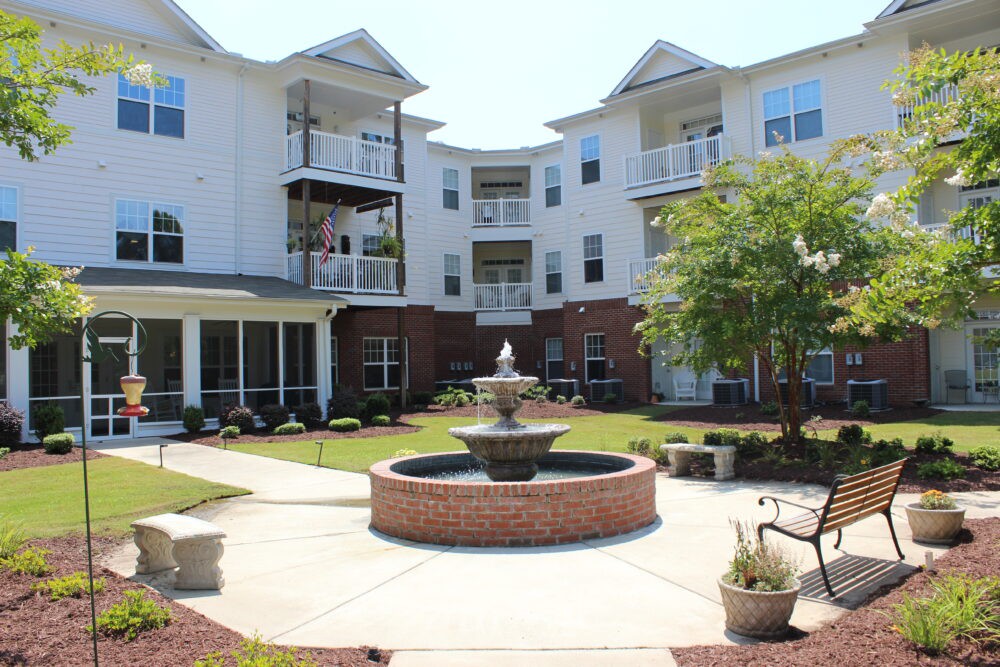 A view of a residential apartment courtyard with a central fountain and surrounding greenery.
