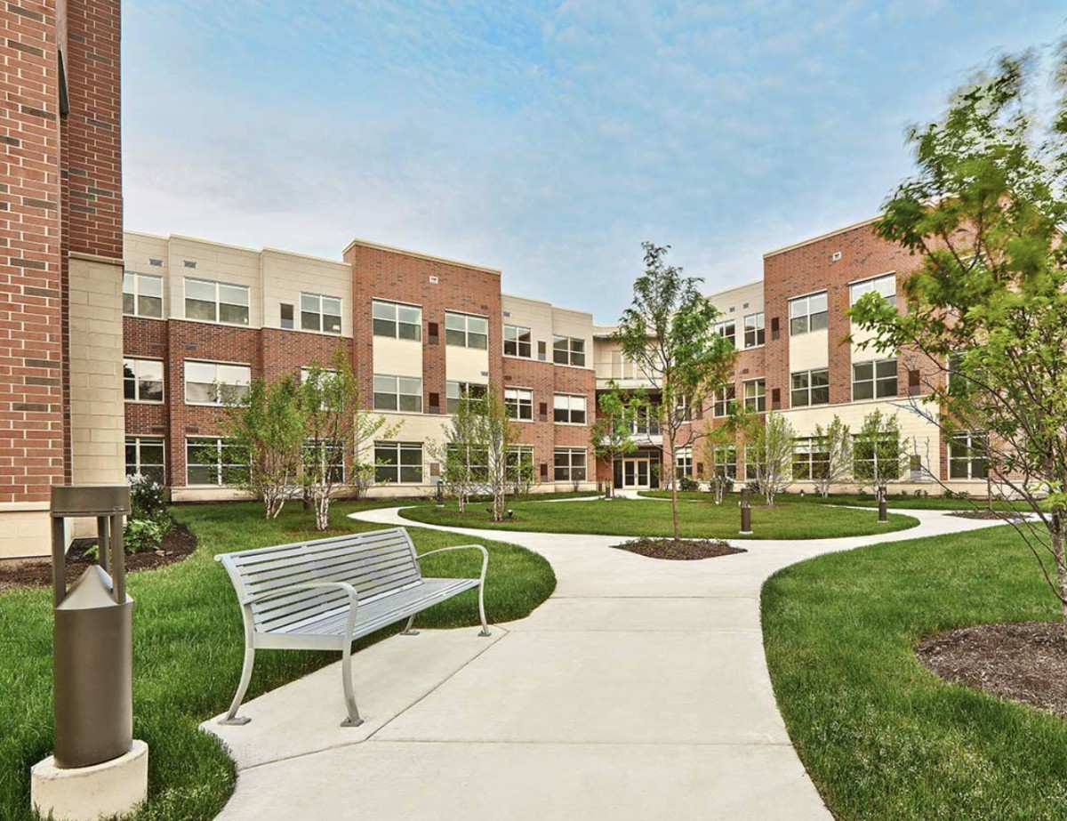 A modern brick building with a landscaped courtyard and winding pathways.