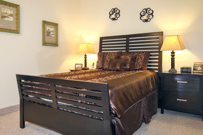 Cozy bedroom with a stylish dark wood bed frame and warm lighting.