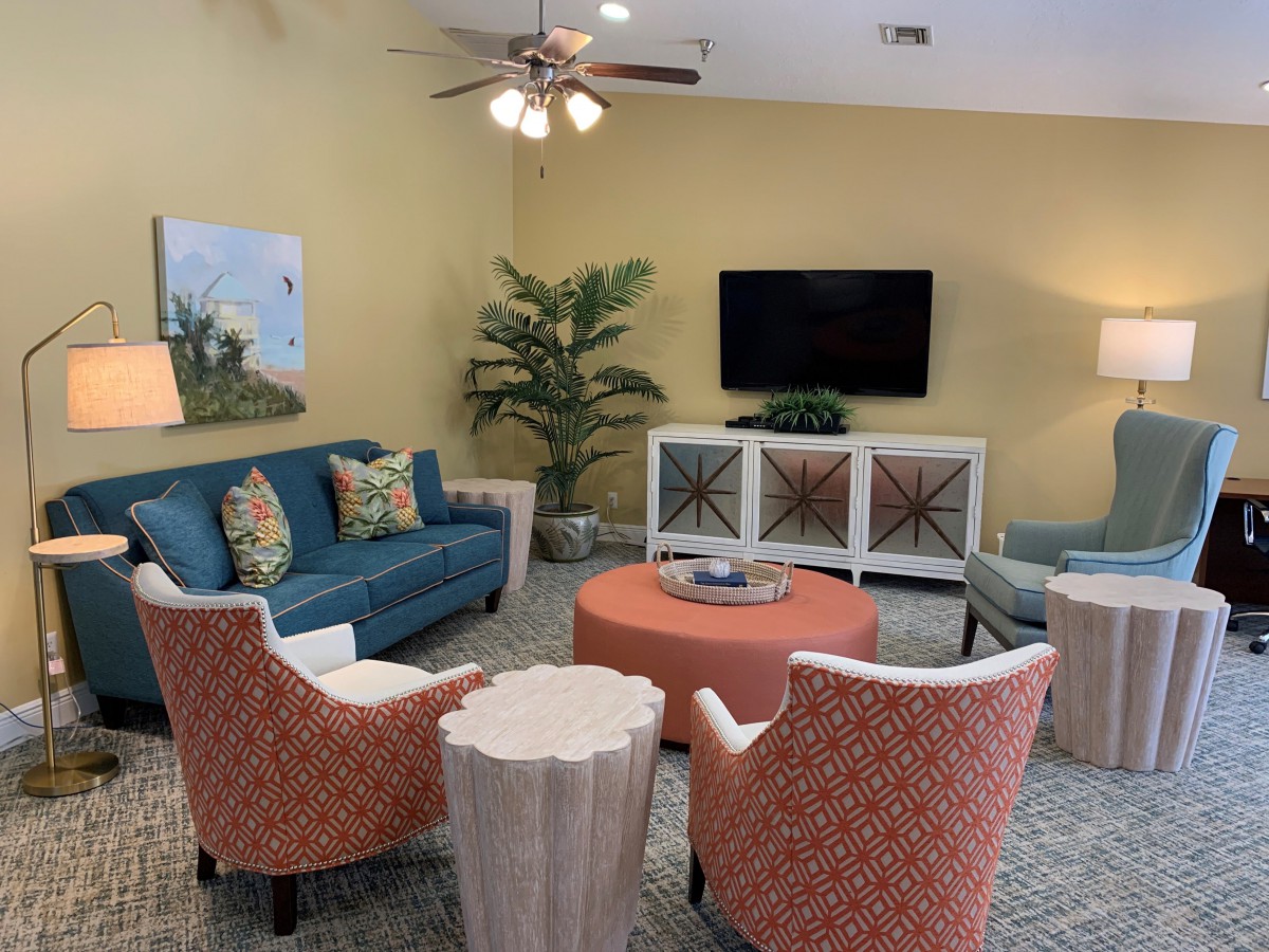 A cozy living room with a blue sofa, orange chairs, and a TV mounted on the wall.