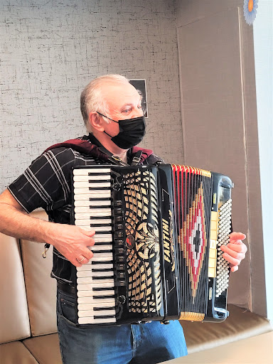 A musician playing the accordion while wearing a mask.