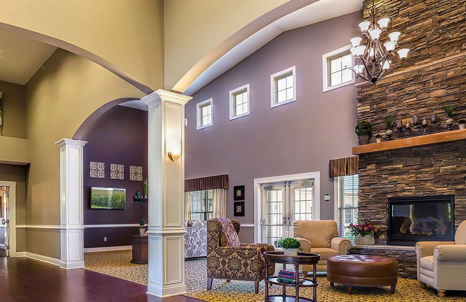A cozy and elegant living room with high ceilings, featuring comfortable seating and a fireplace.