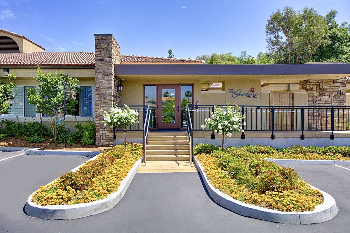 A modern building entrance with well-maintained landscaping and a clear blue sky.