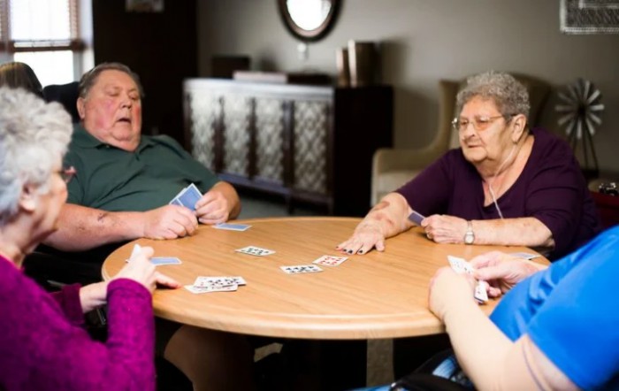 A group of elderly people enjoying a game of cards around a table indoors.