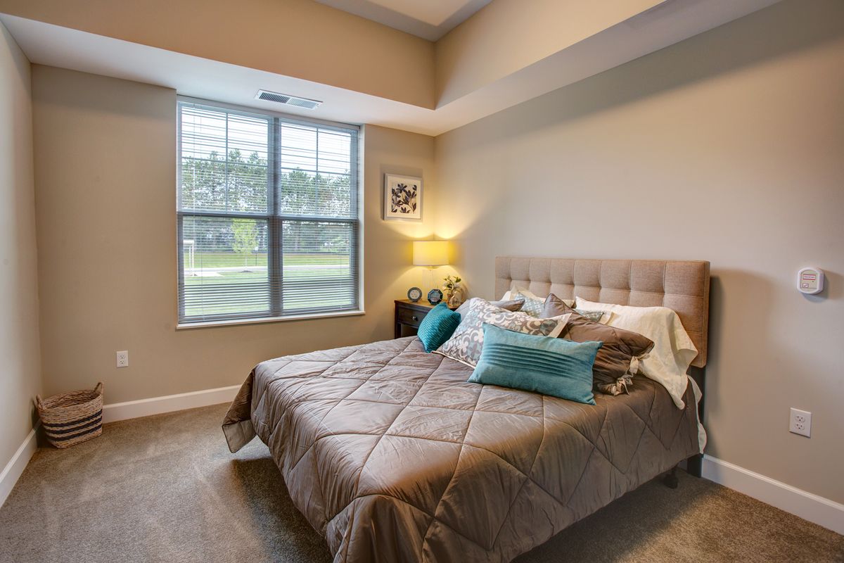 A cozy bedroom with a neatly made bed, soft pillows, and a large window letting in natural light.