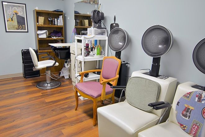 A cozy hair salon interior featuring styling chairs and hooded hair dryers.