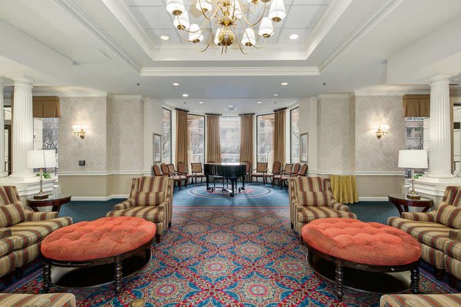 A luxurious lobby with elegant seating, a grand piano, and a chandelier.