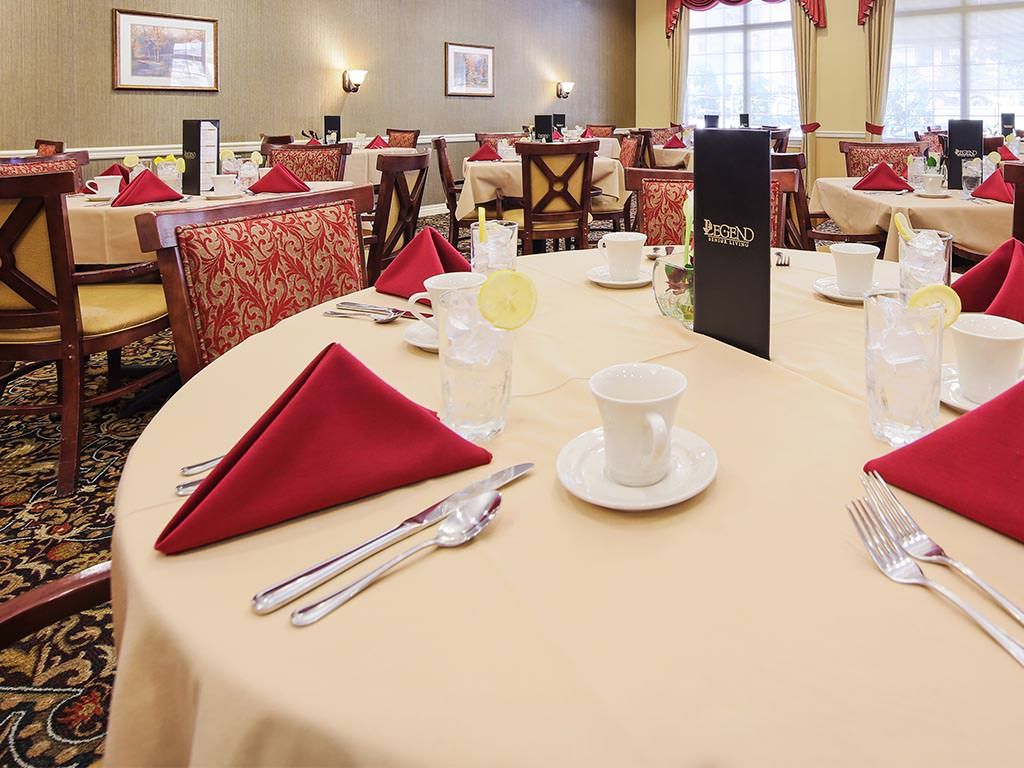 An elegantly set dining table at a restaurant, featuring red napkins and stylish place settings.