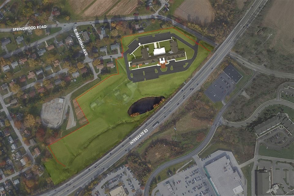 Aerial view of a large building complex surrounded by roads and greenery.