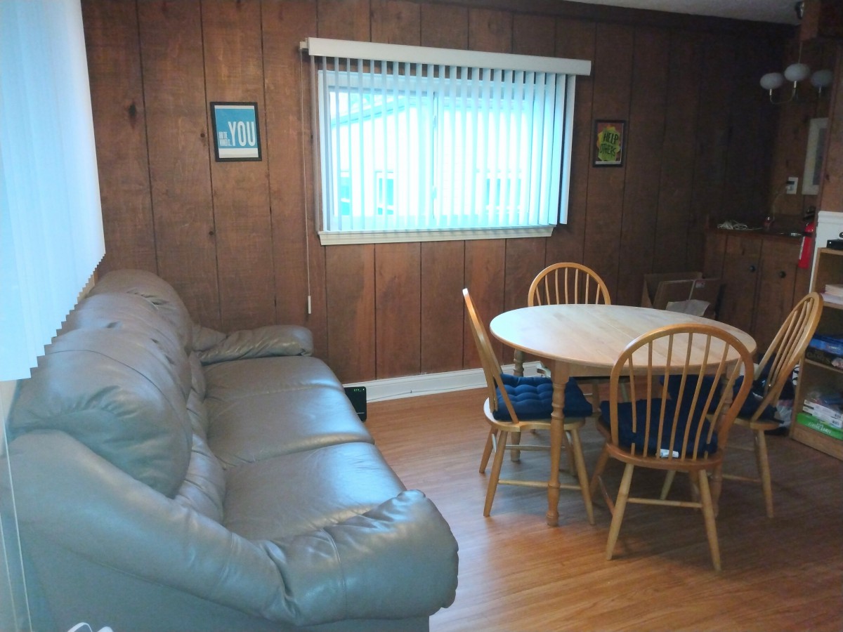A cozy living and dining area featuring wood paneling, a comfortable sofa, and a round dining table with chairs.