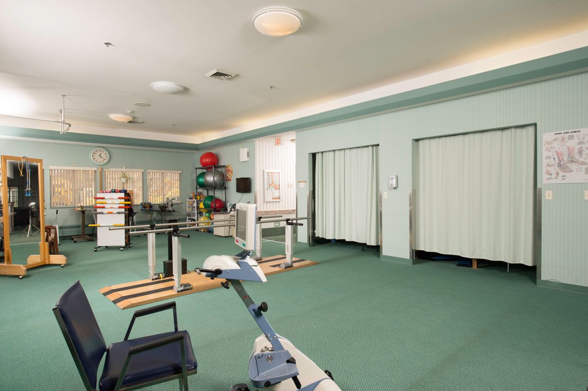 A spacious rehabilitation room equipped with various exercise equipment for physical therapy.