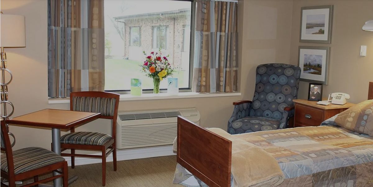 A cozy room with a bed, chair, and window adorned with flowers.